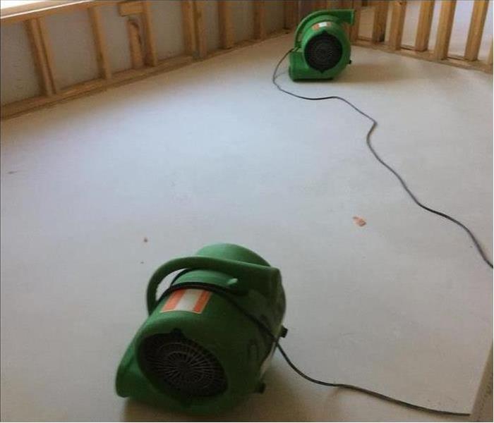 two air movers drying an empty room, drywall has been removed